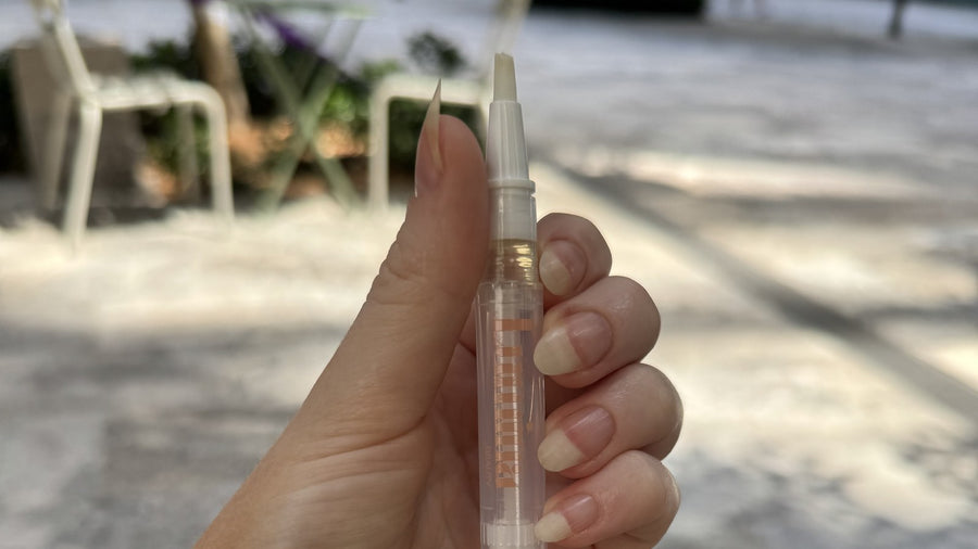 Holding the Lumina Beauty nail oil pen, my own natural nails grown out