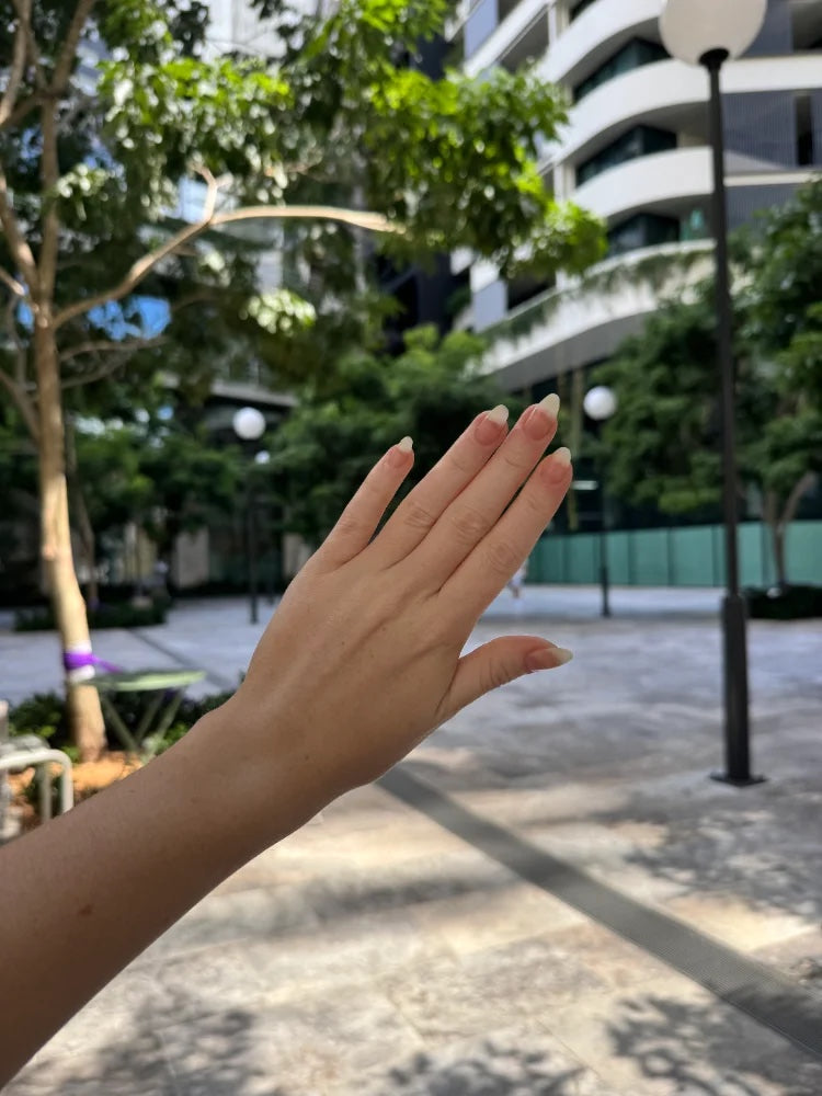 My hand held up outdoors, natural nails grown out