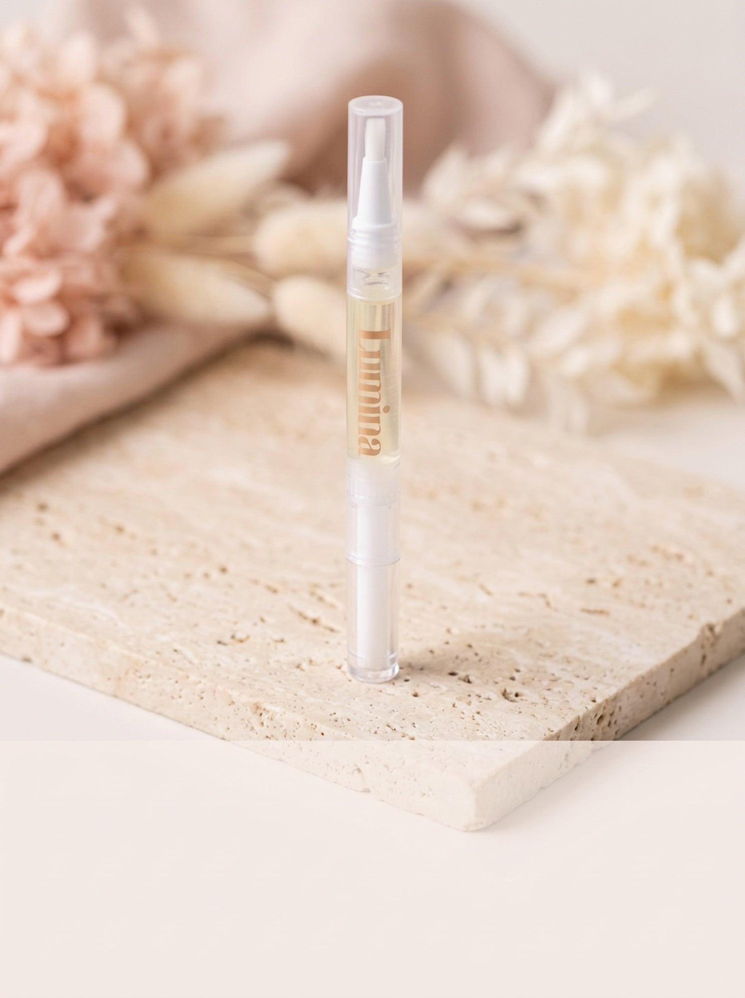 Lumina Beauty nail growth oil pen on travertine with dried florals